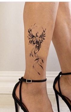 a woman's legs with tattoos and high heels on her feet, one has a flower tattoo on the ankle