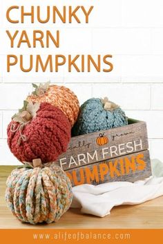 chunk yarn pumpkins sitting on top of a wooden sign with the words farm fresh pumpkins