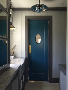 a blue door in a white bathroom next to a counter and sink with two lights