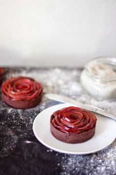 two chocolate cupcakes sitting on top of a white plate next to a knife