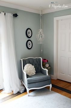 a living room with a chair and chandelier hanging from the ceiling next to a door