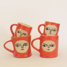 three cups with faces painted on them sitting in front of a white background and one has the shape of a woman's face