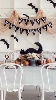 a white table topped with lots of pumpkins and bunting banner hanging from the ceiling