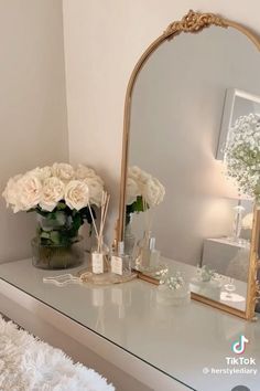 a white dresser topped with a mirror and flowers