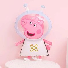 a peppa pig balloon sitting on top of a white table next to a pink wall