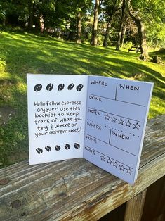 two cards with words written on them sitting on a wooden fence in front of some trees