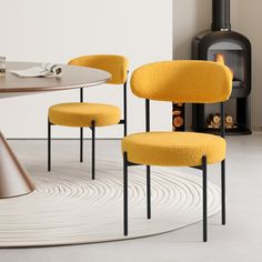 three yellow chairs sitting at a round table in front of a wood burning fire place