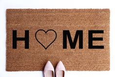 a pair of shoes sitting on top of a door mat with the word home written on it