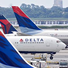 several delta airplanes are parked on the tarmac at an airport in front of other planes