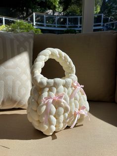 a white basket sitting on top of a couch next to a pillow and throw pillow