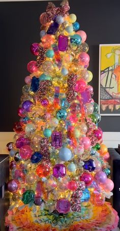 a brightly colored christmas tree with lots of glass ornaments on it's top and bottom