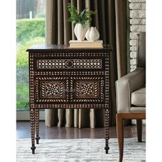 an ornate wooden sideboard with two vases on it and a window in the background