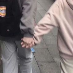 two people are walking down the sidewalk with their hands in each other's pockets