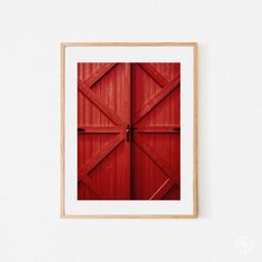 an image of a red barn door on a white wall with wood frame in the foreground