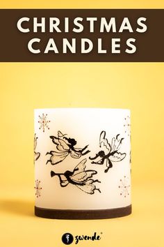 a white candle with black fairy images on it and the words christmas candles above it