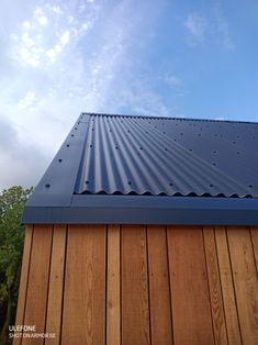 the top of a wooden building with a metal roof and blue sky in the background