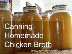 four jars filled with homemade chicken broth sitting on a wooden table next to each other