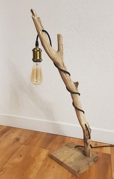 a lamp made out of driftwood with a light bulb on the end and cord wrapped around it