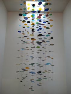 an art installation with many different colored fish hanging from it's sides in a white room