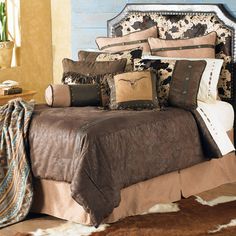 a bed with brown and tan comforters in a room next to a cowhide rug