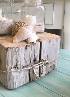 two mason jars with seashells and twine in them on a wooden table