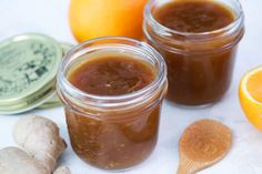 two jars filled with jam next to an orange and ginger