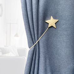 a curtain with a gold star attached to it's side in front of a white couch