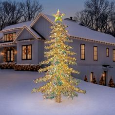 a lighted christmas tree in front of a house