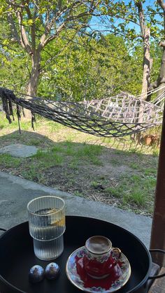 a cup and saucer sitting on a table with a hammock in the background