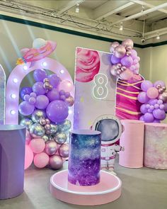 there are balloons and decorations on display in this room, including a cake with purple frosting