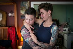 a woman hugging a man with tattoos on his arms