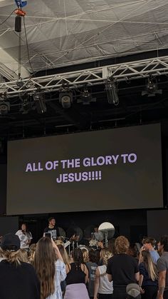 a group of people standing in front of a large screen with the words all of the glory to jesus on it