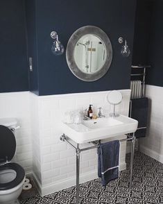 a white sink sitting under a mirror next to a black and white tiled bathroom floor