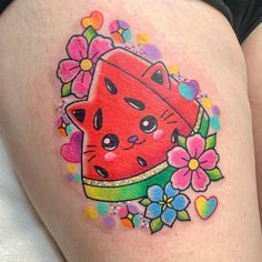 a watermelon tattoo on the thigh with flowers around it and a cat wearing a hat