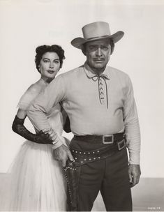 an old black and white photo of two people wearing cowboy hats, one holding the other's hand