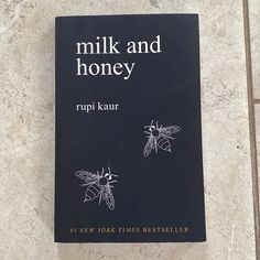 a book about milk and honey with two bees on it's cover sitting on the floor