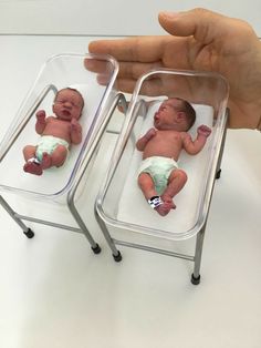 a hand is holding two small babys in plastic cases