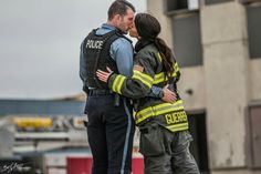 a man and woman are kissing in front of a firetruck with their arms around each other