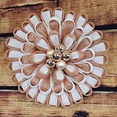 a close up of a flower made out of fabric and metal beads on wood planks