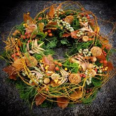 a wreath with leaves, berries and other foliage on top of the wreath is surrounded by autumn colors