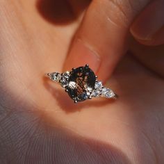 a close up of a person's hand holding a ring with diamonds on it