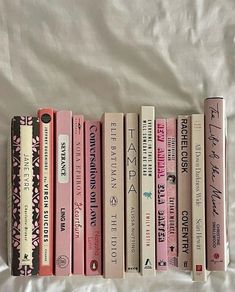 a row of books sitting on top of a white bed sheet next to each other