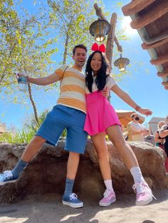 a man and woman are posing for a photo in front of a fountain at disney's animal kingdom