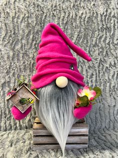 a gnome figurine sitting on top of a wooden box with flowers in it