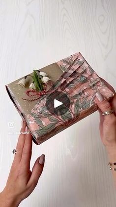 two hands holding a gift box with flowers on the inside and one hand reaching for it