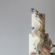 a three tiered white wedding cake with pink and blue flowers