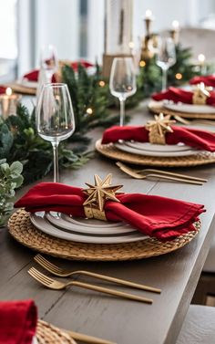 the table is set with red napkins and gold place settings, along with greenery