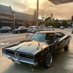 a black muscle car parked in front of a gas station