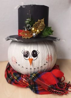 a white pumpkin with a black top hat and plaid scarf