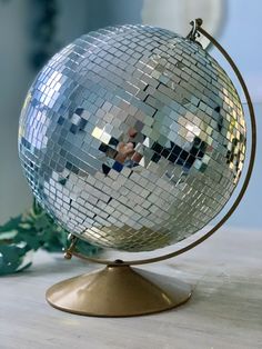 a shiny disco ball sitting on top of a wooden table next to a green plant